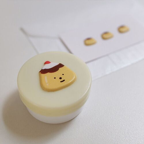 A pudding sticker sits on a small round container, showing how the bakery illustration can add a cheerful accent to an everyday item.