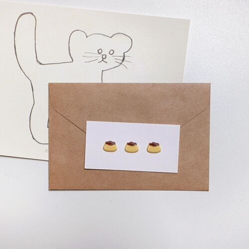 Three mini pudding stickers decorate a white card placed over a brown envelope, offering a simple stationery idea.
