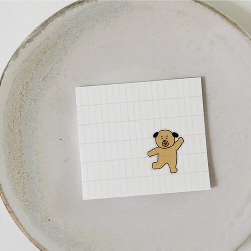 A single tan dancing bear sticker stands on a gridded card, showing its size against the fine square lines.