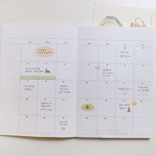 A closer calendar view highlights a pale yellow label, a green clover, and starburst accents placed around written plans.