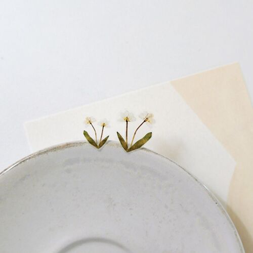 Two white flower stickers are positioned along a rounded dish edge, showing how the designs can frame an object.