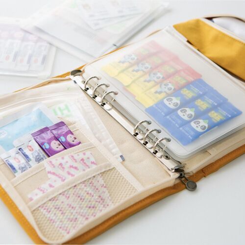 An open A5 binder displays the pocket set alongside a yellow zippered organizer and assorted stored stationery.