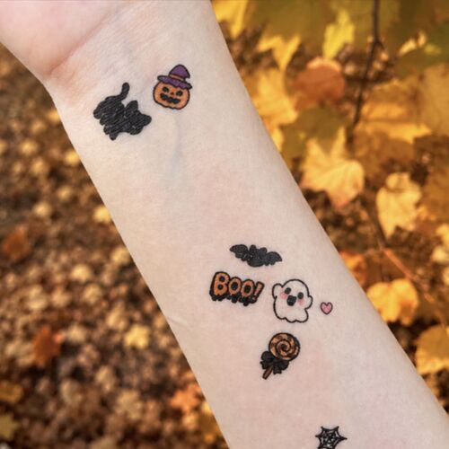 Several Cute Halloween designs appear transferred across an arm, including a ghost, BOO lettering, a bat, a heart, and a lollipop.