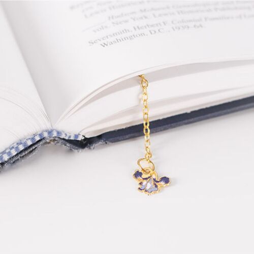 The Iris bookmark hangs from an open book, with its matching flower charm visible below the page.