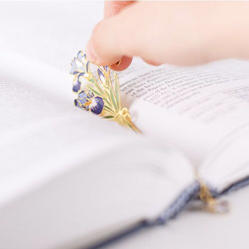 A hand places the Iris bookmark between open book pages, showing its slim profile in use.