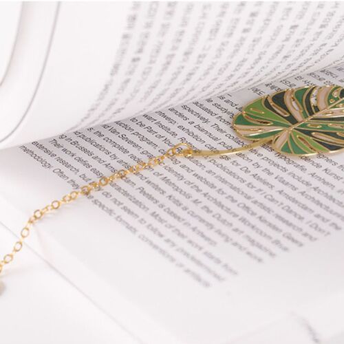 The Monstera Leaf charm hangs beneath a dark book cover, creating a simple green-and-gold page marker.