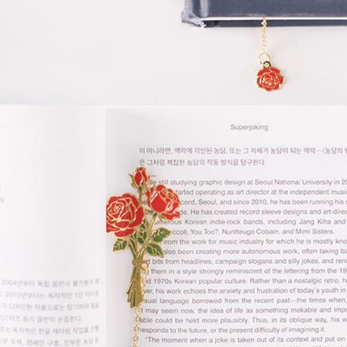 A hand places the Sunflower bookmark between open pages, showing its lightweight metal form.