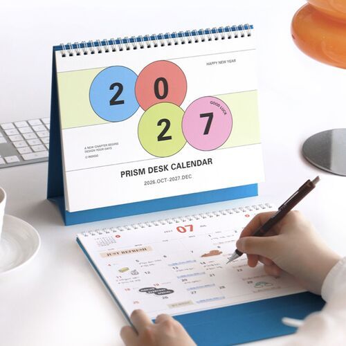 A blue-bound calendar sits near a keyboard, highlighting its upright format for an organized workspace.
