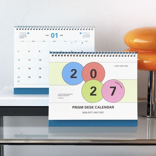 The desk calendar is presented on a shelf with books, showing how it fits neatly into a styled workspace.