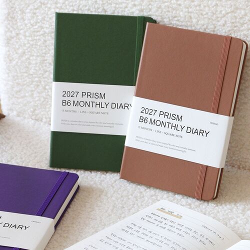 Moss Green and Mocha Mousse planners rest together on a soft textured surface, highlighting their understated covers.