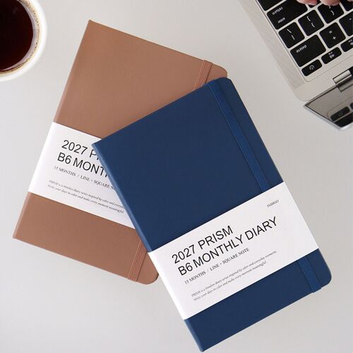 Mocha Mousse and Santorini planners sit beside a laptop and coffee, framing the planner for desk use.
