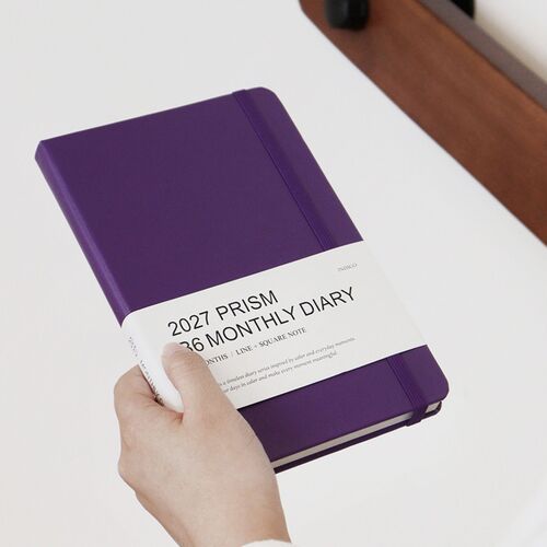 Sunset Purple is held at an angle, with the white product band still wrapped around the hardcover.