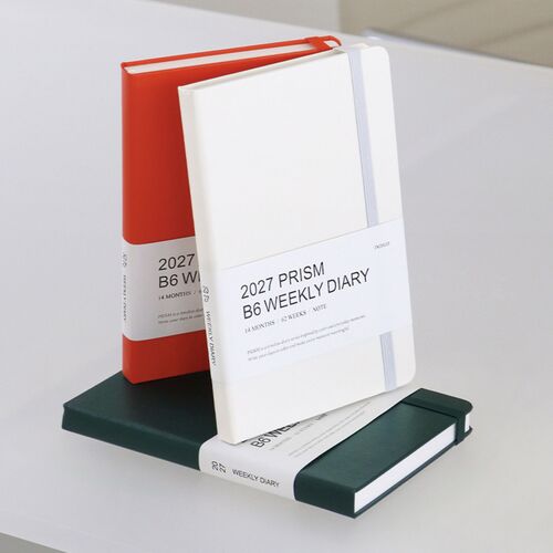 The Tomato Red planner stands beside another closed copy, clearly showing the hardcover thickness and white paper edges.