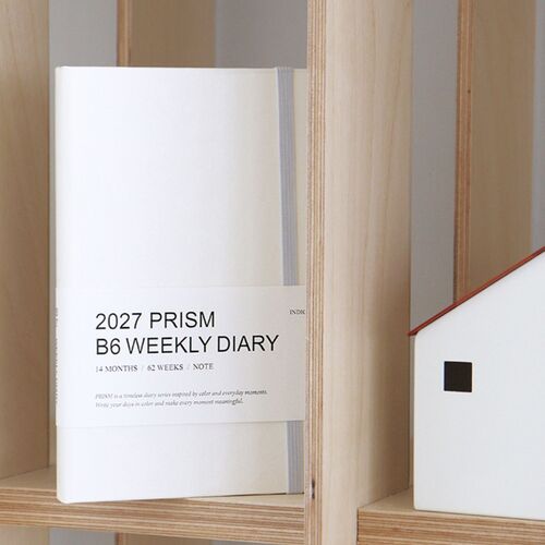 The Tomato Red planner is displayed upright in a bright interior setting with its paper belly band attached.