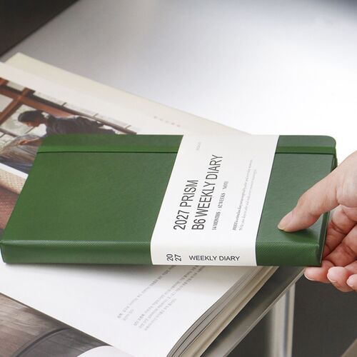 A dark Forest planner is held open, showing the cover boards, page block, and flexible binding.