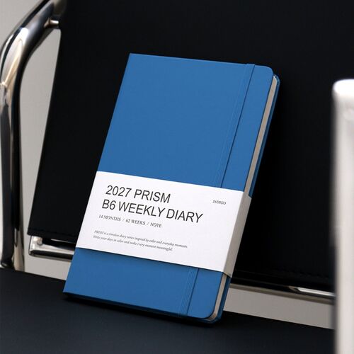 A Milky Blue planner is held in both hands, showing its plain back cover and rounded edges.