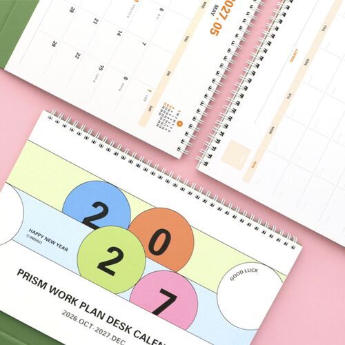 The colorful cover fills the foreground while several open calendar pages reveal the spiral-bound format and spacious grids.