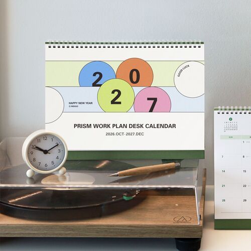 A dated page is shown in use with handwritten entries, while the green stand supports the calendar behind it.