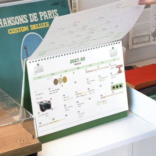 The calendar is positioned beside an open laptop and notebook, fitting naturally into a focused work setting.