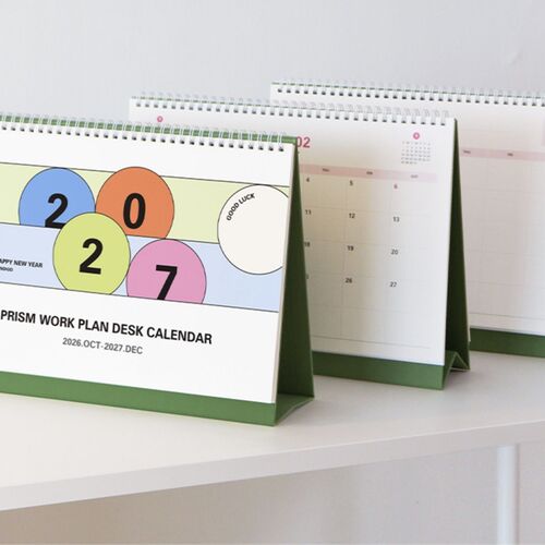 A wide desk scene shows the calendar surrounded by stationery, books, and a computer for everyday planning.