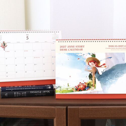 Two calendar pages are shown together, contrasting an open writing layout with the illustrated Anne Story cover.