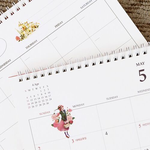 A hand turns the calendar page, showing the smooth spiral binding and ample space for handwritten appointments.
