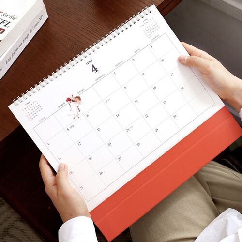 A close view shows handwritten plans, highlighted reminders, and playful illustrations arranged across the monthly grid.