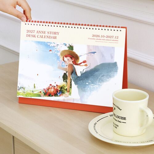 The calendar rests beside a cup and notebook, showing how its broad desktop format fits naturally into a work area.
