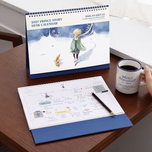 The scheduler stands beside a coffee cup while an open monthly page shows roomy boxes for writing and planning.