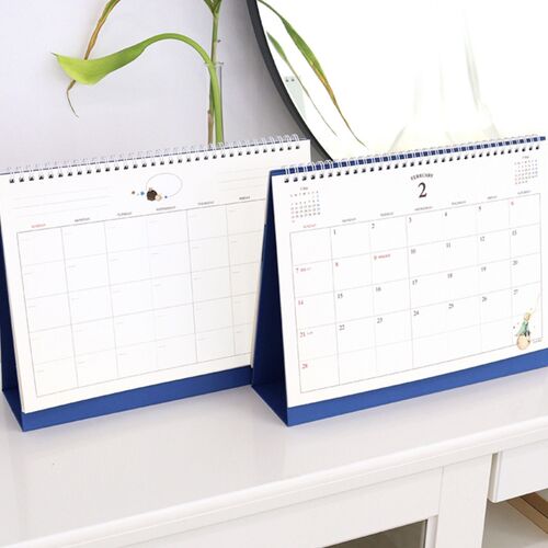 Two standable calendars display dated monthly layouts on a white shelf, making the upright format easy to compare.