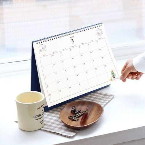 The calendar stands on a dark round table, where the illustrated cover adds a quiet decorative touch.
