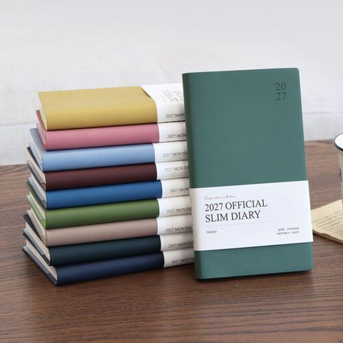 Multiple closed schedulers are arranged in a neat vertical stack, showing the range of soft PU cover colors and slim format.