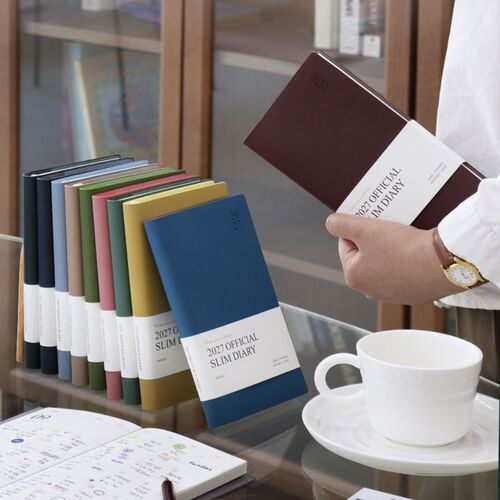The Mustard cover is held upright, showing its soft texture, rounded corners, and subtle embossed 2027 marking.