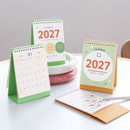 Photo 2: A Smile Green calendar displays its fold-out triangular base and spiral binding beside an open monthly planning page.