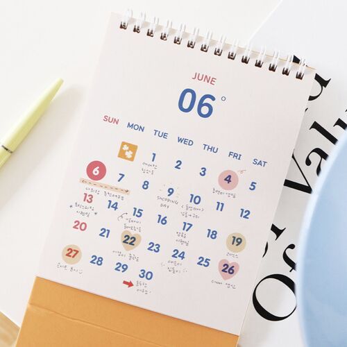 Photo 10: A hand places a heart sticker onto a July calendar date, with the included heart-patterned sticker sheet visible below.