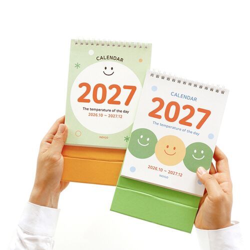 Photo 5: Two calendars are held side by side to show the different cover designs, spiral tops, and standing bases.