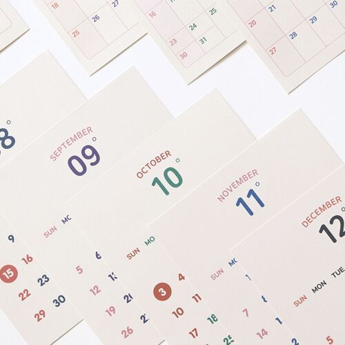 Photo 16: Several dated calendar pages are arranged in a fan, showing large month numerals and color-coded dates from late summer onward.