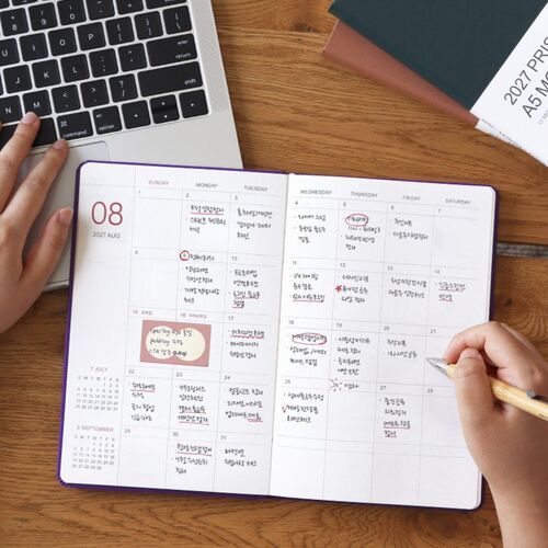 An open monthly spread sits beside a laptop, with spacious date boxes ready for appointments, reminders, and notes.