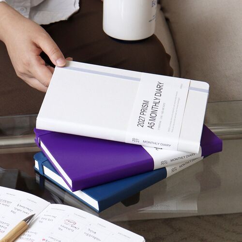 The planner is opened on a tabletop and filled with handwritten entries across its monthly calendar grid.