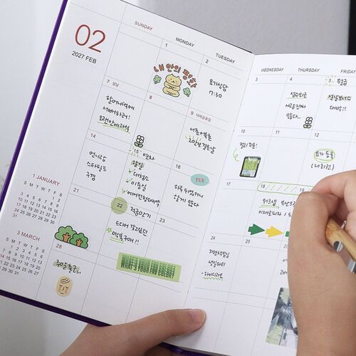 The open monthly planner rests near a laptop, giving a clear look at the spacious two-page writing layout.