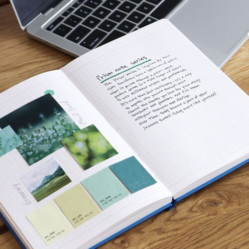 A lined page is open beside a laptop with a pen nearby, creating a practical setup for daily note-taking.