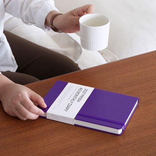 The Black planner sits on a desk with a pen and laptop, giving the cover a clean, understated presentation.