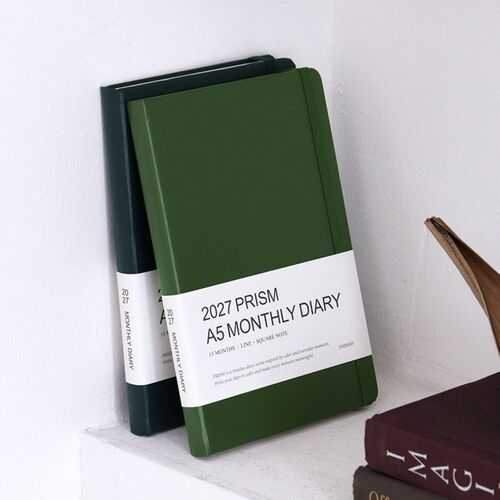 A stack of planners shows the thickness of the hardcover books and the variety of available cover colors.