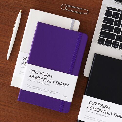 A Moss Green planner is held over a shoulder bag, showing its portable size for commuting or travel.