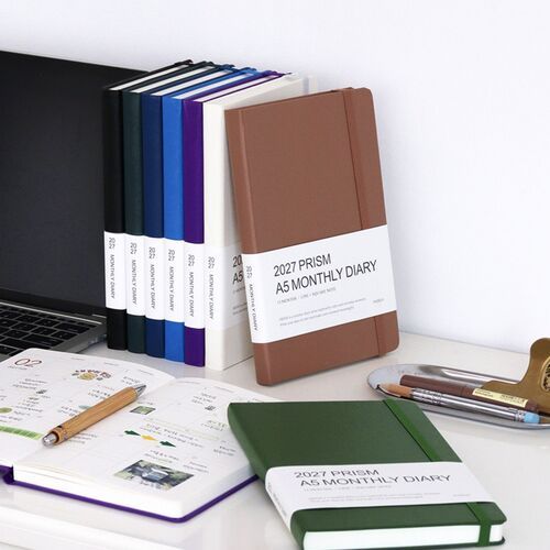 Several planners are arranged with a laptop and open calendar pages, presenting the collection as a coordinated desk setup.