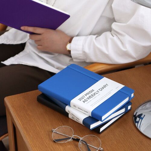 Mocha Mousse rests on stacked planners beside a pen, creating a calm desk scene for planning sessions.
