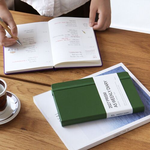 A stack of planners shows the varied cover colors and white page blocks from a side angle.