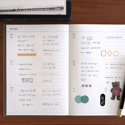 The open planner sits beside photographs and stationery, suggesting use for memory keeping and journaling.