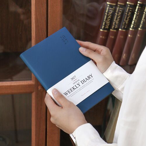 A stack of schedulers displays multiple cover colors and the consistent white 2027 diary bands.