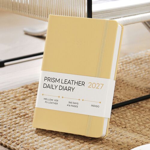 Green Mellow rests on a striped fabric background, showing its centered year embossing and vertical elastic band.
